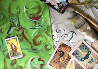 tarot cards, brushes and paints on a table
